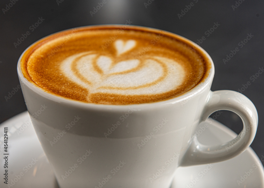 Taza blanco con cafe con diseño de arte latte en primer plano con foco diferenciado. Taza blanco con cafe con diseño de arte latte en primer plano con foco diferenciado.