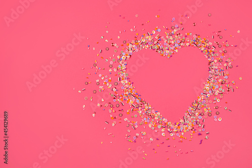 Heart made of confetti on a pink background. Love.
