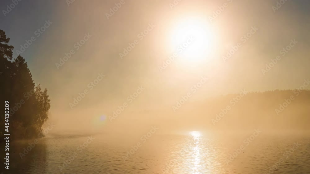 Thick, heavy fog over the river. Mystical autumn misty dawn. The morning sun breaks through the thick fog. Beautiful autumn landscape. Morning fog at sunrise. Timelapse. Thick, heavy fog over the river. Mystical autumn misty dawn. The morning sun breaks through the thick fog. Beautiful autumn landscape. Morning fog at sunrise. Timelapse.