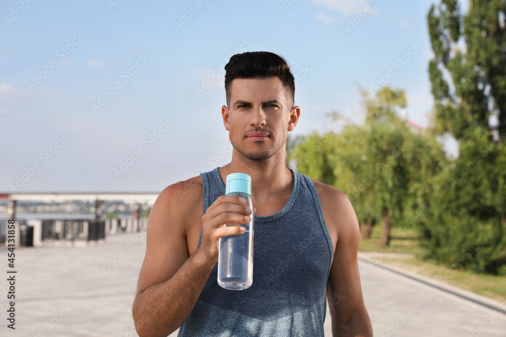 Handsome man in sportswear with bottle of water outdoors on sunny day Handsome man in sportswear with bottle of water outdoors on sunny day