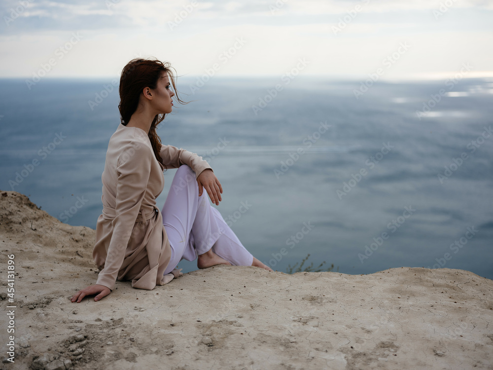 beautiful woman posing near rocks in the sand elegant style