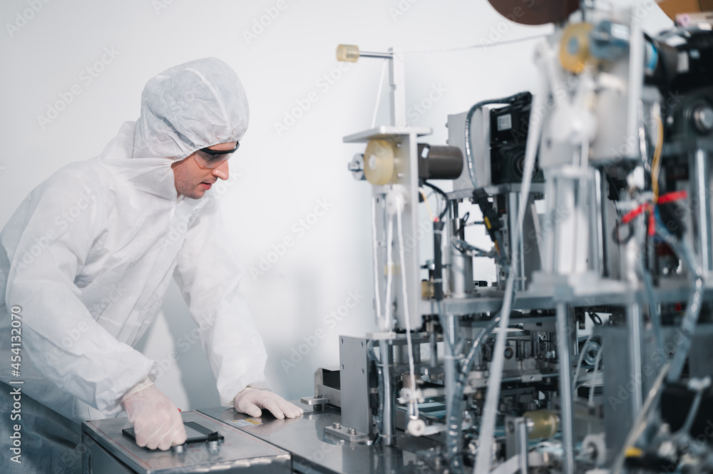 Scientists wearing protective clothing Inspect mask making machines in a laboratory at an industrial plant. Anti-virus production warehouse. concept of safety and prevention coronavirus covid-19. Scientists wearing protective clothing Inspect mask making machines in a laboratory at an industrial plant. Anti-virus production warehouse. concept of safety and prevention coronavirus covid-19.