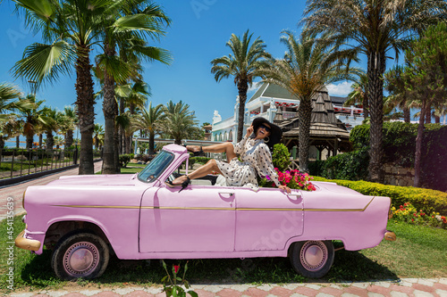 Summer fashion. Beautiful sexy elegant woman in polka dot dress near the pink car on Cuba Havana. Spring and summer fashion model concept. Vintage and retro style. Luxury travel. © marcink3333