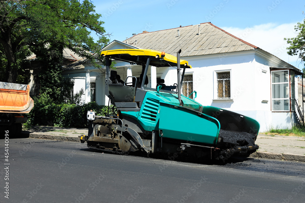 Asphalt paver working on city street. Road repair
