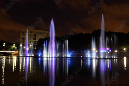 Colorful blue white illuminated musical fountains on the Svisloch River at summer night on sky background , a beautiful view of Minsk , a famous national landmark of the capital of Belarus