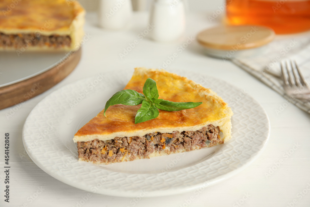 Piece of delicious pie with minced meat on white table Piece of delicious pie with minced meat on white table