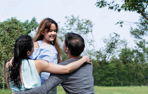 Happy cute daughter hugging daddy and mom love isolated on green. Portrait of a happy family of three. Happy family is having fun outdoors. Father, mother and girl are spending