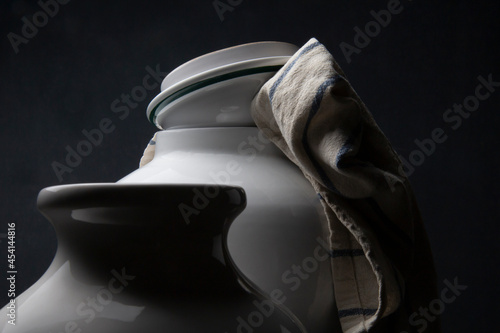 Due vasi in ceramica bianca e uno strofinaccio da cucina su fondo scuro   photo