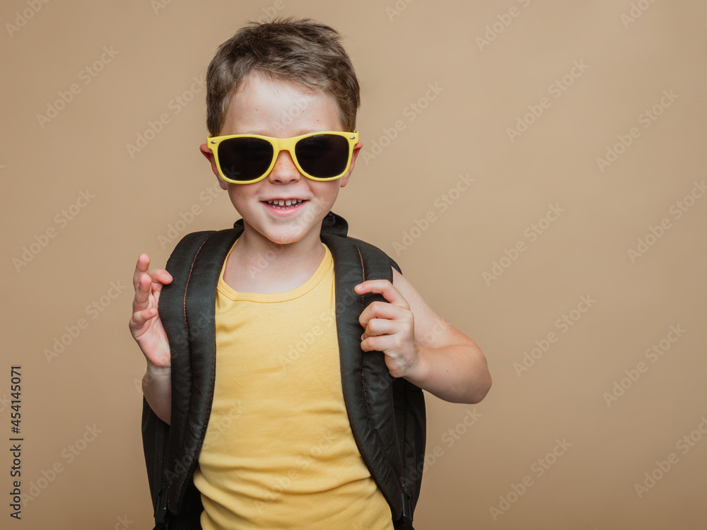 Smiling pupil with backpack and in sunglasses in studio Smiling pupil with backpack and in sunglasses in studio