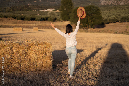 Cheerful Asian woman standing near haystack in field photo