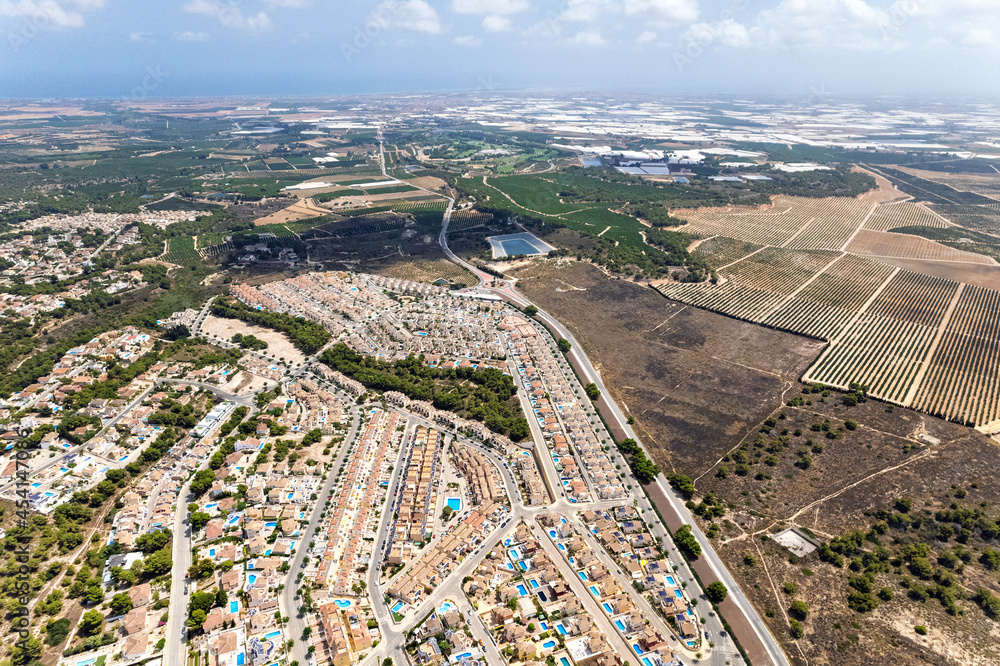 Drone point of view countryside meadows and Pinar de Campoverde residential district view from above. Summer day. Costa Blanca, Province of Alicante, Spain