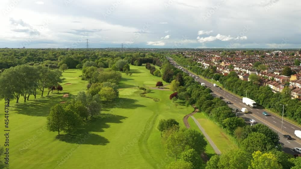 cultivated green public park with mowed lawn and trees located at busy multilane highway. Afternoon footage of golf course. cultivated green public park with mowed lawn and trees located at busy multilane highway. Afternoon footage of golf course.