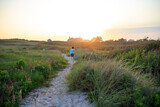 Boy running on a sandy path at sunset