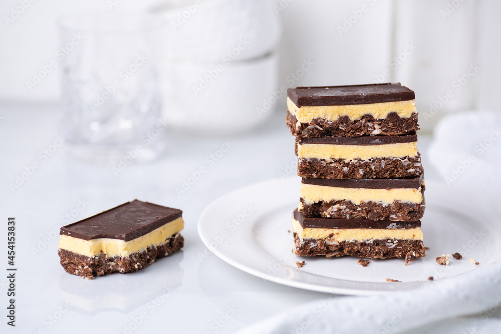 A stack of Nanaimo bars - a traditional Canadian dessert - in a white kitchen A stack of Nanaimo bars - a traditional Canadian dessert - in a white kitchen