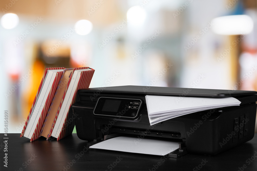Stack of books and home printer against blurred background