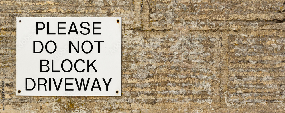 Do Not Block Driveway sign on stone wall, background banner image Do Not Block Driveway sign on stone wall, background banner image