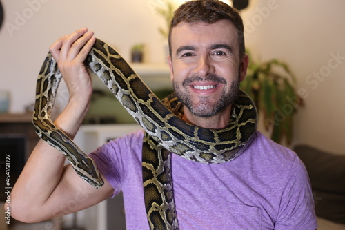 Man with large Burmese python at home