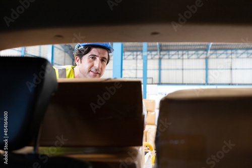 male factory worker loading and moving boxes in to the car from warehouse storage © offsuperphoto