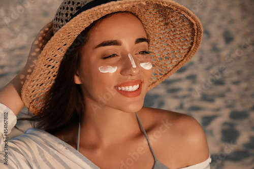 Fotografía Happy young woman with sun protection cream on face at beach