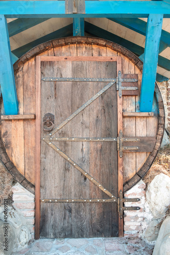 Old wooden grunge brown door with iron door handle on a large barrel © Luka