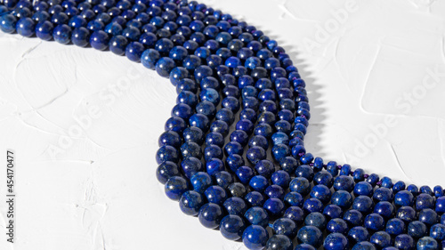 Blue necklaces made from natural lazurite  are beautifully laid out on a white surface.  Isolated lapis lazuli jewelry. Round beads.  photo