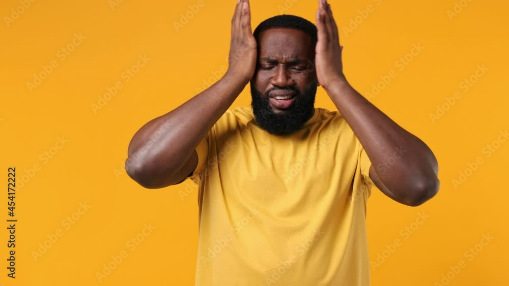 Sick ill tired young african american man 20s wears orange t-shirt put hands on head rub temples having headache suffering from migraine feel seedy isolated on plain yellow background studio portrait Sick ill tired young african american man 20s wears orange t-shirt put hands on head rub temples having headache suffering from migraine feel seedy isolated on plain yellow background studio portrait