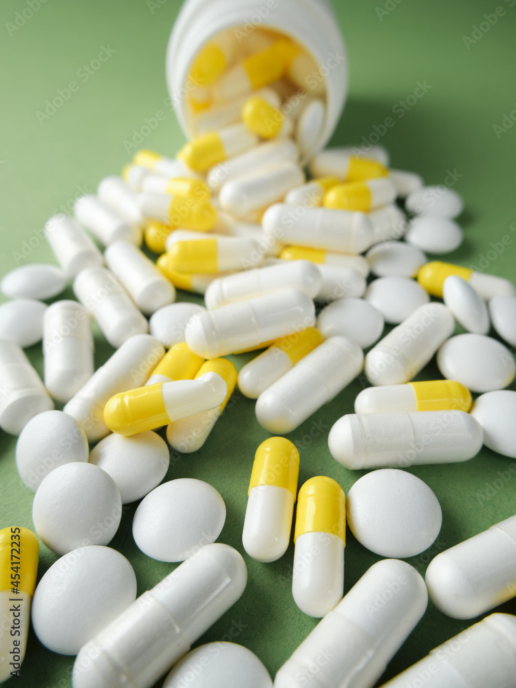 The pills are scattered on the table. Tablets on the green background. Medicinal tablets, capsules. The pills are scattered on the table. Tablets on the green background. Medicinal tablets, capsules.