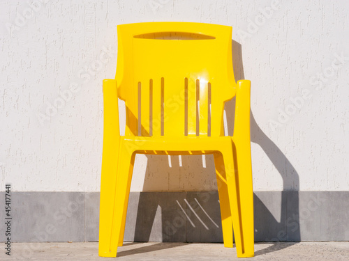 Yellow plastic chair near grey wall. photo