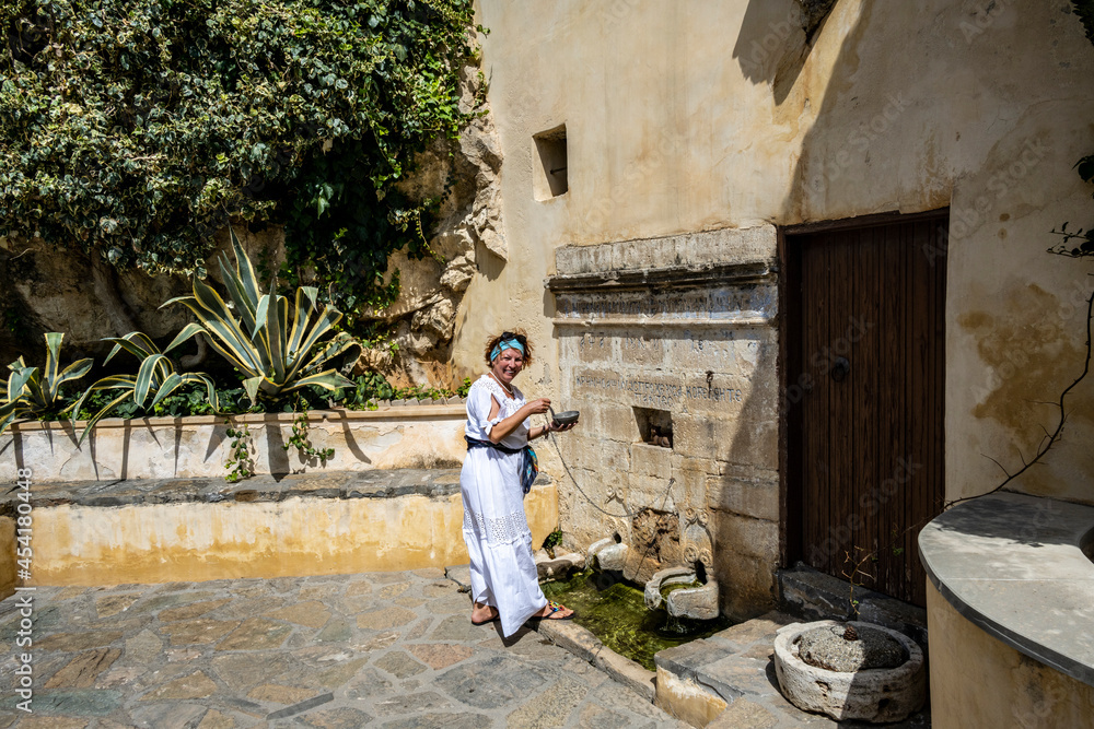 woman in white on the background of the sea mountains blue sky and ancient buildings on the island of Crete 