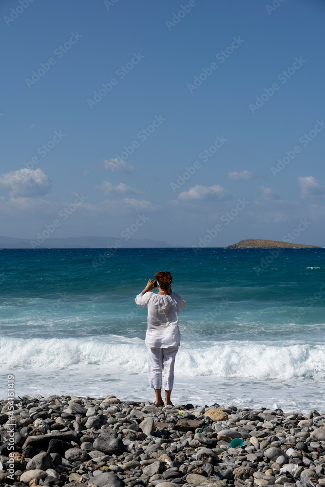 woman in white on the background of the sea mountains blue sky and ancient buildings on the island of Crete 