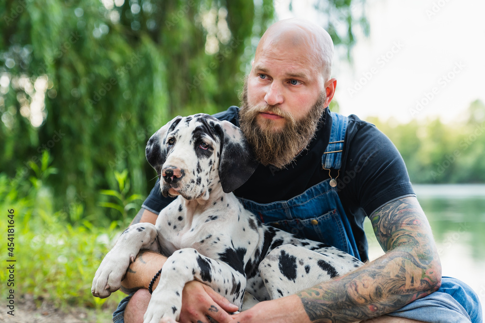 Serious bearded man with dog on lakeshore Serious bearded man with dog on lakeshore