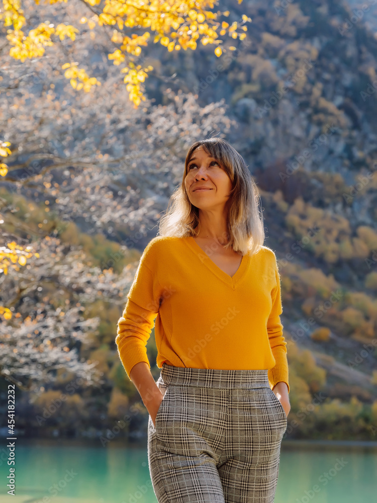 Caucasian woman at crystal lake in autumnal mountains. Mountain lake and traveller