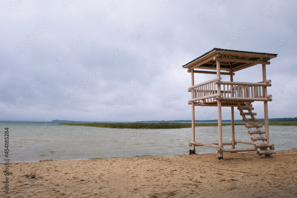 Wooden lifeguard tower on the stormy shore of the lake in Ukraine. Off-season. Copy space. 