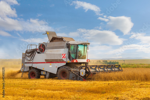 Agricultural machine harvester for harvesting ripe grain crops. Rotary combine working in the wheat field at the end of summer. Farming agricultural background.