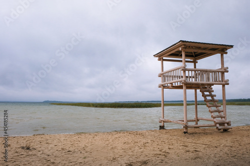 Wooden lifeguard tower on the stormy shore of the lake in Ukraine. Off-season. Copy space.  © Ganna Zelinska