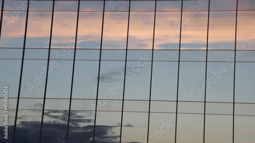 Timelapse video with sunset clouds reflection running. Modern building windows reflect color clouds 