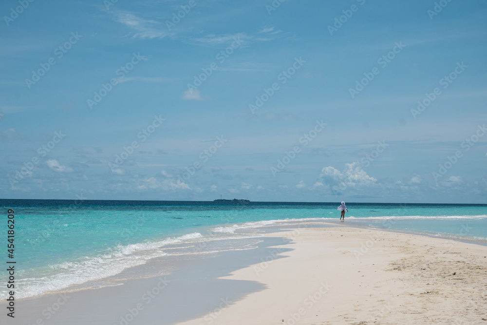 Tropical nature. A happy and free girl walks near the ocean on a beach with white sand. Travel and recreation.