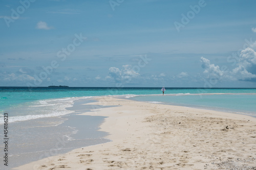 Tropical nature. A happy and free girl walks near the ocean on a beach with white sand. Travel and recreation.