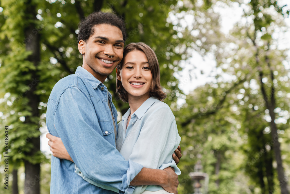 Young happy mixed-race couple students hugging embracing together in city park walking on romantic date. Love and relationship concept. Love at first sight.