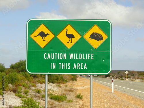 Caution wildlife road sign in yellow and green colors. Kangaroo, emu and echidna figures. Western Australia, nearby Perth.