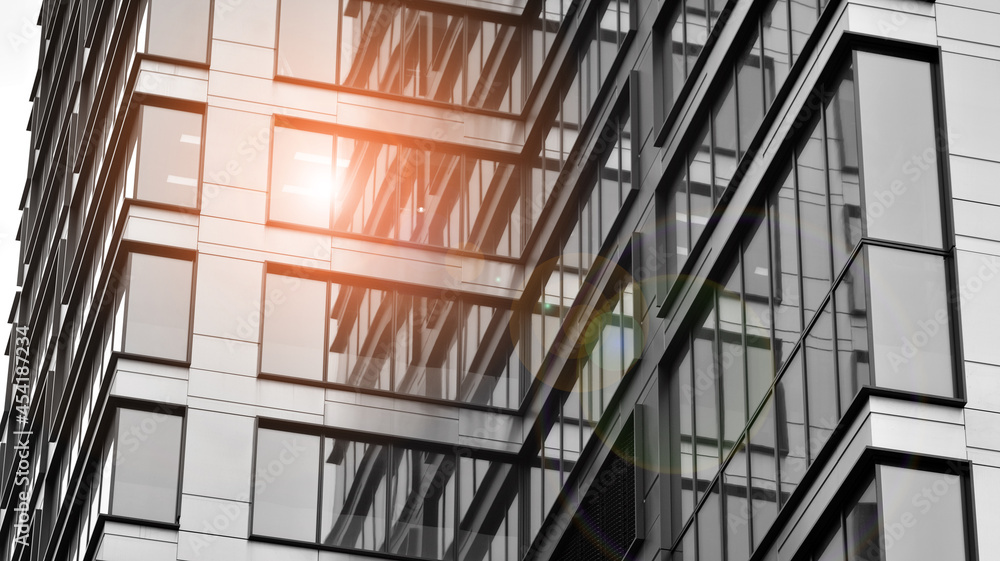 Modern architectural details. Modern glass facade with a geometric pattern. Contemporary corporate business architecture. Red sun on horizon. Black and white toned image. Modern architectural details. Modern glass facade with a geometric pattern. Contemporary corporate business architecture. Red sun on horizon. Black and white toned image.
