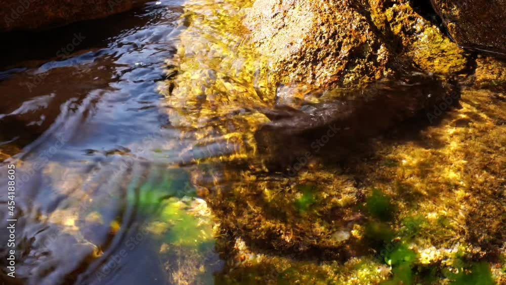 water flowing between rocks in sun light water flowing between rocks in sun light