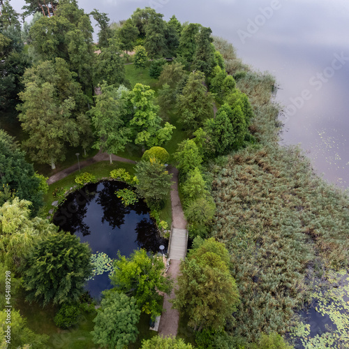 Aerial, drone nature photography of a pond with deciduous trees and a path. Calm water surface, a place to tranquil. photo