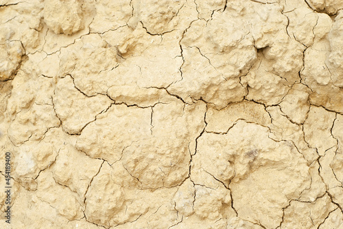 Dry yellow earth with cracks close up. The concept of global warming, cataclysms and drought.
