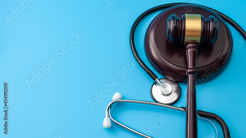 Healthcare legislation and regulation, medical malpractice decision and health care injury personal attorney concept with gavel and stethoscope isolated on blue background with copy space photo