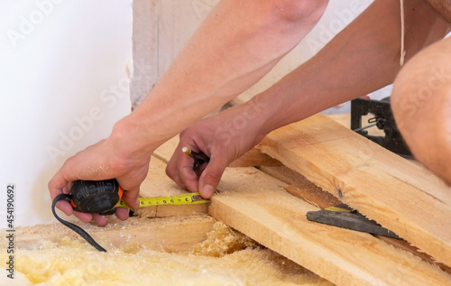 A man cuts a board with an electric saw. Repair of the floor in the house. Selective focus.