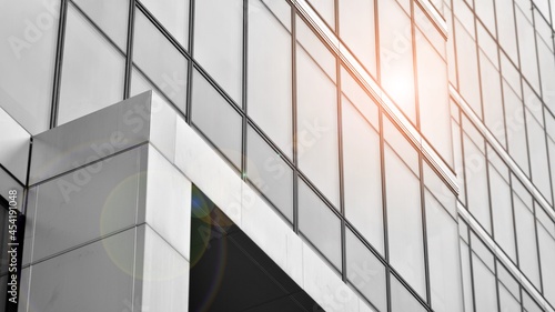 Modern architectural details. Modern glass facade with a geometric pattern. Contemporary corporate business architecture. Red sun on horizon. Black and white toned image.