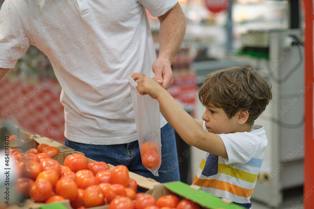 Little boy with Dad choosing tomatoes food in fruit vegetable shopping store Little boy with Dad choosing tomatoes food in fruit vegetable shopping store