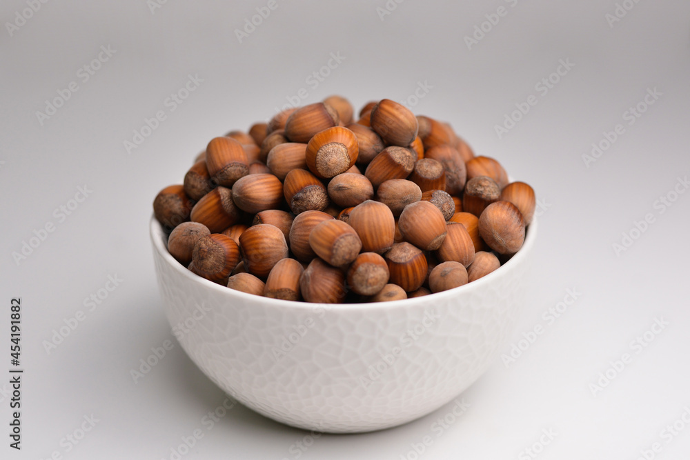 Organic hazelnut. Full bowl of hazelnuts in bowl. Hazelnut in white bowl isolated on white background. Organic hazelnut. Full bowl of hazelnuts in bowl. Hazelnut in white bowl isolated on white background.
