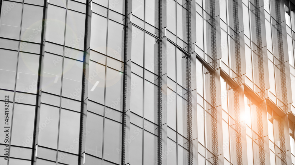 Modern architectural details. Modern glass facade with a geometric pattern. Contemporary corporate business architecture. Red sun on horizon. Black and white toned image. Modern architectural details. Modern glass facade with a geometric pattern. Contemporary corporate business architecture. Red sun on horizon. Black and white toned image.